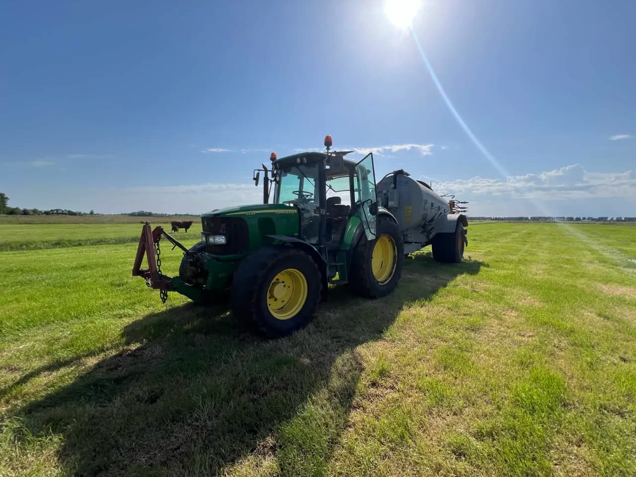 John Deere trekker met mesttank in een groen weiland